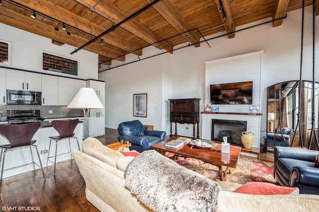 1243 S Wabash Ave Unit 302, Chicago, IL 60605 - living area featuring wooden ceiling with exposed beams, rail lighting, dark wood-type flooring, a towering ceiling, and a glass covered fireplace