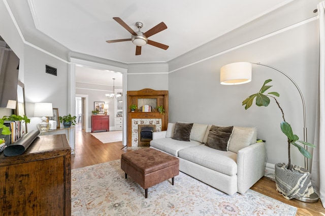 1128 W Wolfram St Unit 2, Chicago, IL 60657 - living room featuring ceiling fan, wood finished floors, a stone fireplace, a chandelier, and crown molding