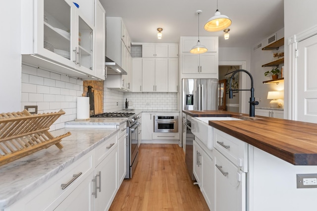 1128 W Wolfram St Unit 2, Chicago, IL 60657 - kitchen featuring wood counters, appliances with stainless steel finishes, white cabinets, and backsplash