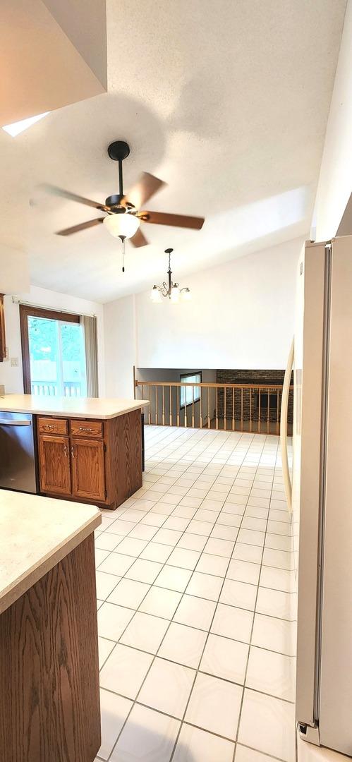 18068 Jason Ln, Lansing, IL 60438 - kitchen featuring stainless steel dishwasher, freestanding refrigerator, light countertops, a ceiling fan, and brown cabinetry
