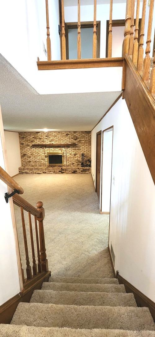 18068 Jason Ln, Lansing, IL 60438 - staircase featuring carpet, brick wall, and a fireplace