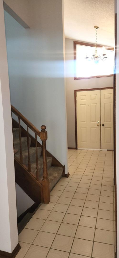 18068 Jason Ln, Lansing, IL 60438 - foyer entrance with a chandelier, stairs, and light tile patterned flooring