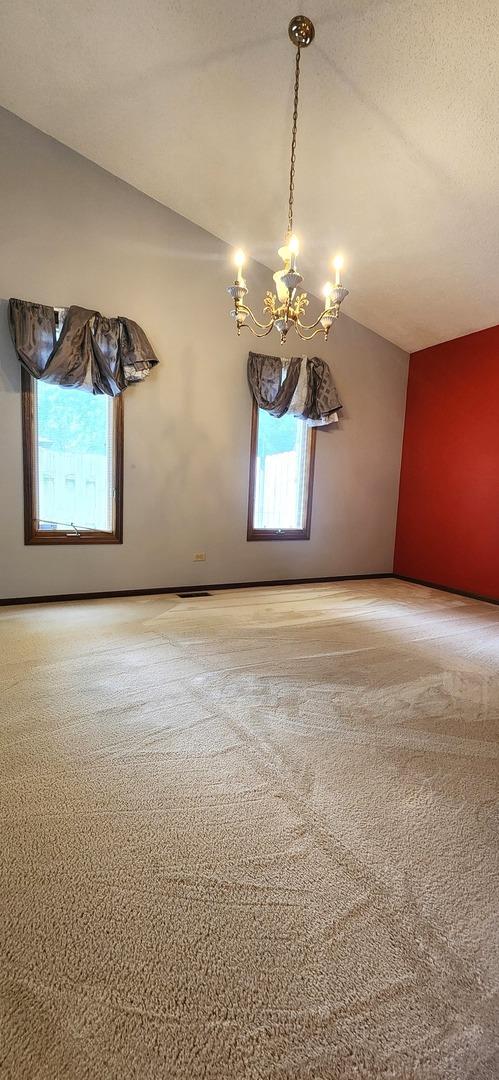 18068 Jason Ln, Lansing, IL 60438 - empty room with plenty of natural light, a chandelier, lofted ceiling, and carpet