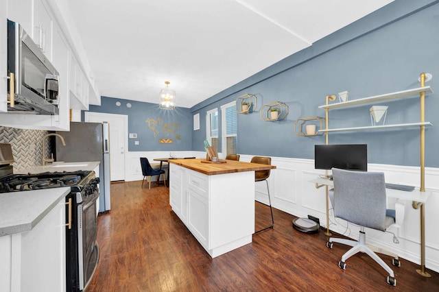 3137 N Monticello Ave, Chicago, IL 60618 - kitchen featuring stainless steel appliances, wood counters, white cabinets, wainscoting, and a kitchen bar