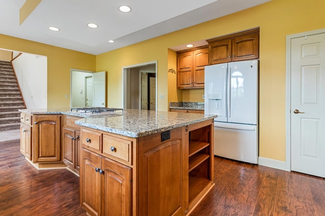 3208 Countrybend Ln, Champaign, IL 61822 - kitchen featuring white fridge with ice dispenser, stainless steel gas stovetop, dark wood-style flooring, light stone counters, and brown cabinets