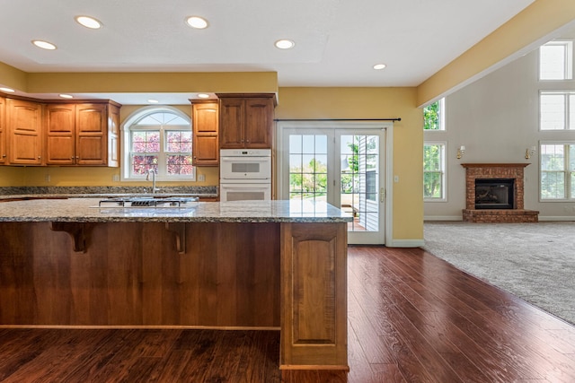 3208 Countrybend Ln, Champaign, IL 61822 - kitchen with white double oven, dark stone countertops, a kitchen breakfast bar, dark wood finished floors, and open floor plan