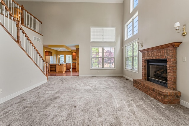 3208 Countrybend Ln, Champaign, IL 61822 - unfurnished living room featuring a towering ceiling, carpet floors, a brick fireplace, and stairway