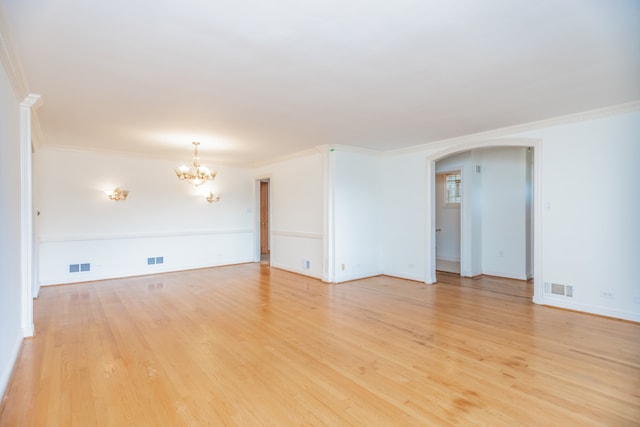 2519 Sunnyside Ave, Westchester, IL 60154 - empty room featuring a chandelier, arched walkways, light wood-style flooring, and crown molding