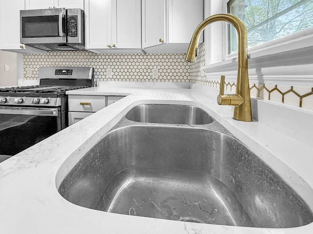 2914 Ridge Rd, Lansing, IL 60438 - kitchen view of appliances with stainless steel finishes, decorative backsplash, white cabinetry, and light stone countertops