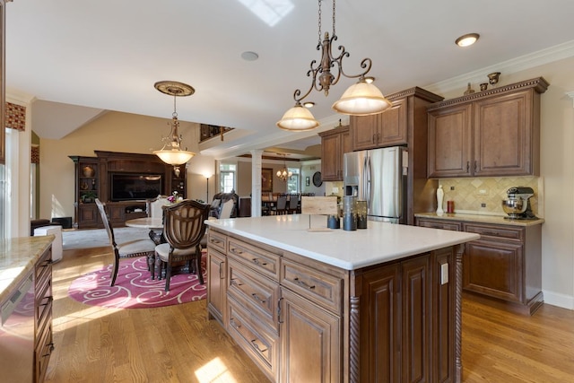 1835 Rizzi Ln, Bartlett, IL 60103 - kitchen with stainless steel appliances, ornate columns, light wood-style floors, light countertops, and crown molding