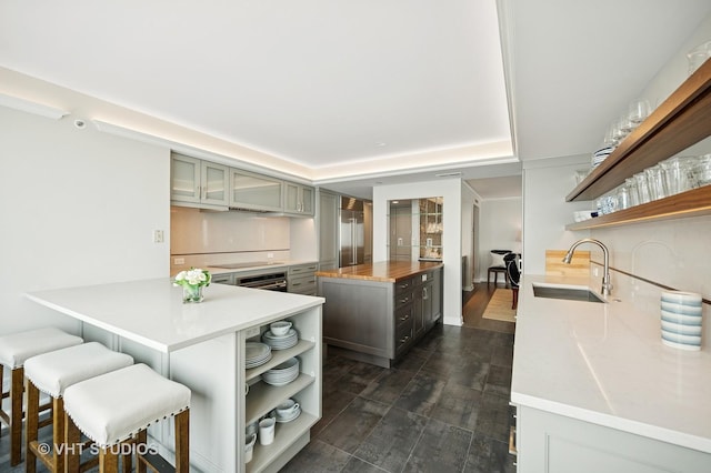132 E Delaware Pl Unit 5106, Chicago, IL 60611 - kitchen featuring open shelves, gray cabinets, a kitchen island, a kitchen breakfast bar, and dark wood-style flooring