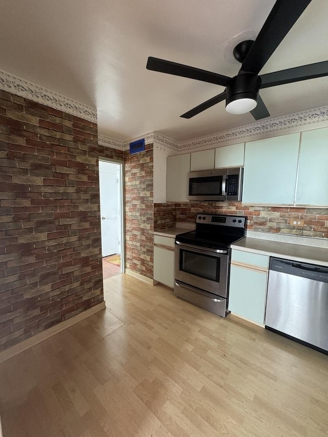 6301 N Sheridan Rd Unit 24C, Chicago, IL 60660 - kitchen featuring stainless steel appliances, brick wall, light countertops, a ceiling fan, and decorative backsplash