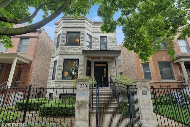 1230 W Cornelia Ave, Chicago, IL 60657 - view of front facade featuring stone siding, a fenced front yard, and a gate