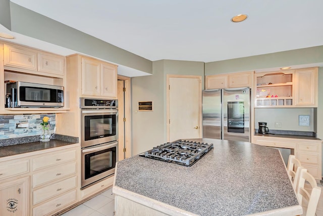 16924 Yearling Crossing Dr, Orland Park, IL 60467 - kitchen with stainless steel appliances, a center island, light brown cabinetry, dark countertops, and tasteful backsplash