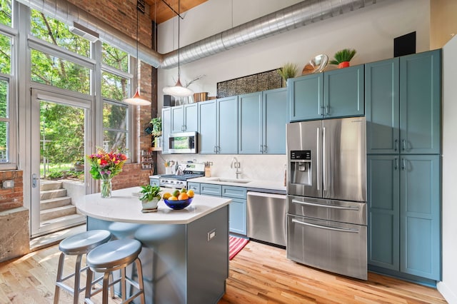 2111 W Churchill St Unit 112, Chicago, IL 60647 - kitchen with appliances with stainless steel finishes, light countertops, a towering ceiling, light wood-style flooring, and a kitchen island