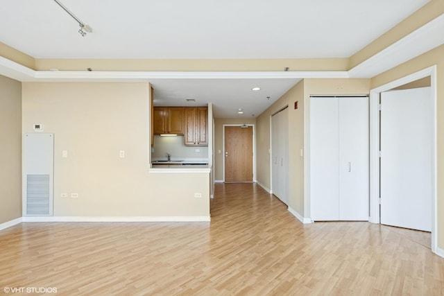 77 S Evergreen Ave Unit 707, Arlington Heights, IL 60005 - unfurnished living room featuring light wood-style flooring, recessed lighting, a sink, baseboards, and a heating unit