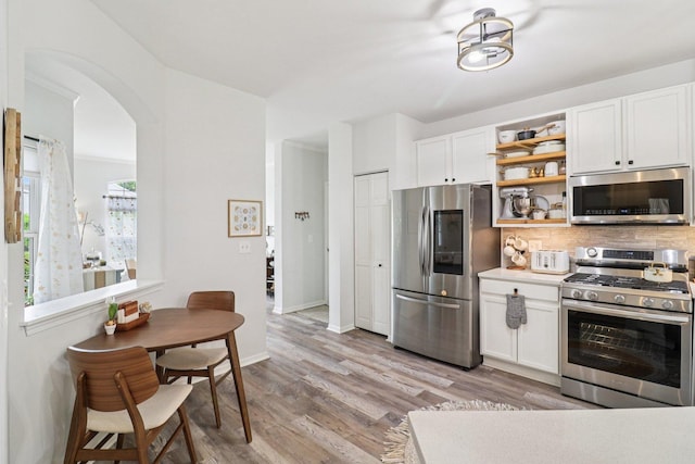 245 Grays Dr, Oswego, IL 60543 - kitchen featuring stainless steel appliances, arched walkways, white cabinets, and decorative backsplash