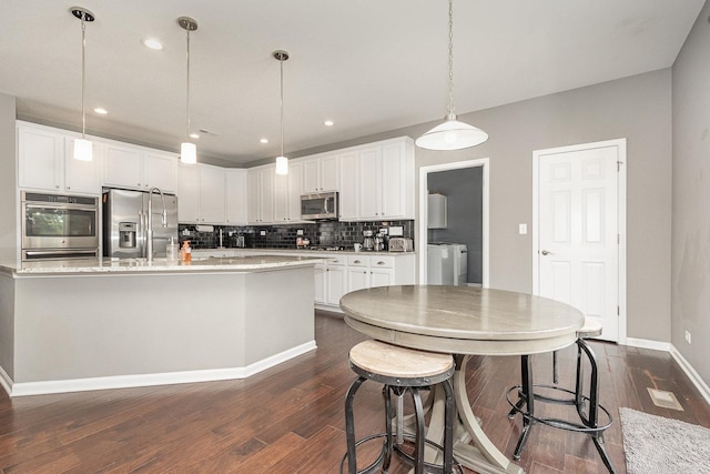 14904 S Morgan Ln, Plainfield, IL 60544 - kitchen featuring stainless steel appliances, washing machine and dryer, dark wood finished floors, backsplash, and white cabinets