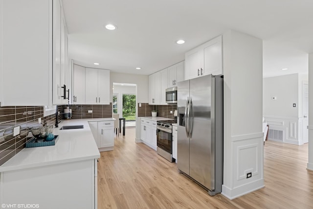 20534 Arcadian Dr, Olympia Fields, IL 60461 - kitchen with appliances with stainless steel finishes, a sink, white cabinetry, light wood-style flooring, and backsplash