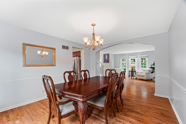 1440 Monarch Cir, Naperville, IL 60564 - dining room featuring arched walkways, a chandelier, light wood-type flooring, and baseboards
