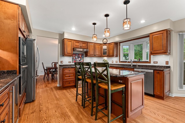 1440 Monarch Cir, Naperville, IL 60564 - kitchen with appliances with stainless steel finishes, a sink, brown cabinets, under cabinet range hood, and light wood-type flooring