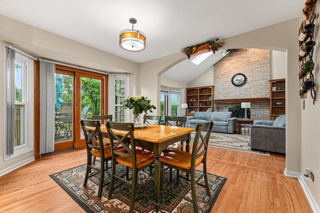 1440 Monarch Cir, Naperville, IL 60564 - dining space featuring plenty of natural light, arched walkways, light wood-type flooring, vaulted ceiling, and a brick fireplace
