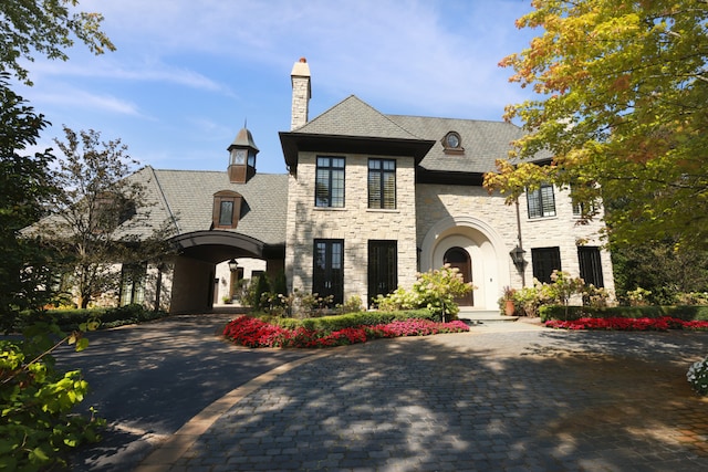 15W120 60th St, Burr Ridge, IL 60527 - french country home featuring stone siding, a high end roof, decorative driveway, and a chimney