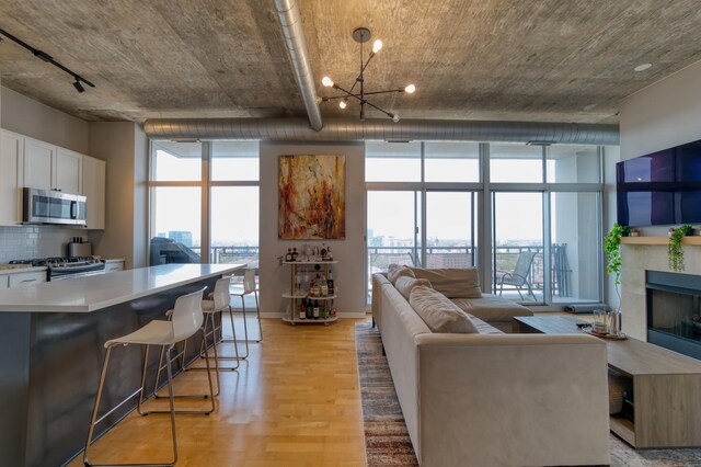 700 N Larrabee St Unit 1315, Chicago, IL 60654 - living room with light wood-style floors, a wall of windows, a chandelier, a fireplace, and baseboards