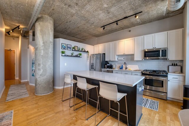 700 N Larrabee St Unit 1315, Chicago, IL 60654 - kitchen with stainless steel appliances, track lighting, tasteful backsplash, a kitchen island, and light wood-type flooring