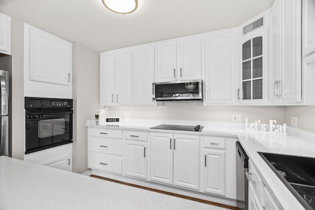 6007 N Sheridan Rd Unit 37H, Chicago, IL 60660 - kitchen with black appliances, white cabinetry, glass insert cabinets, a sink, and light countertops