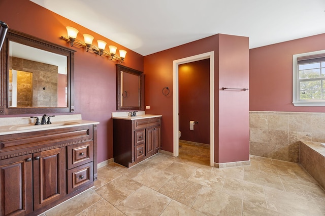 16266 W Mohawk Ct, Lockport, IL 60441 - bathroom featuring two vanities, tiled tub, and stone finish floors
