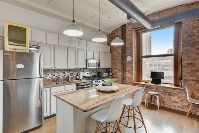 1322 S Wabash Ave Unit 407, Chicago, IL 60605 - kitchen featuring stainless steel appliances, brick wall, a sink, light wood-style flooring, and a breakfast bar