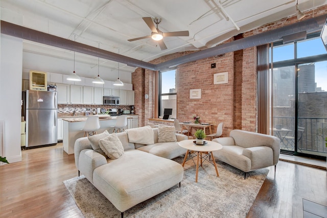 1322 S Wabash Ave Unit 407, Chicago, IL 60605 - living area featuring brick wall, light wood finished floors, ceiling fan, plenty of natural light, and a towering ceiling