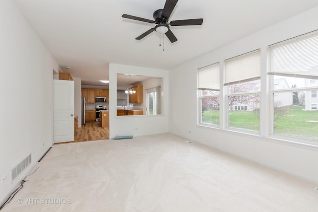 1110 Oakhill Dr, Aurora, IL 60502 - unfurnished living room featuring healthy amount of natural light, light carpet, a ceiling fan, and a chandelier