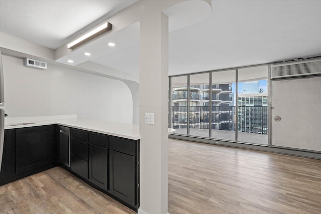300 N State St Unit 5225, Chicago, IL 60654 - kitchen with dark cabinetry, floor to ceiling windows, light wood finished floors, light countertops, and a wall mounted air conditioner