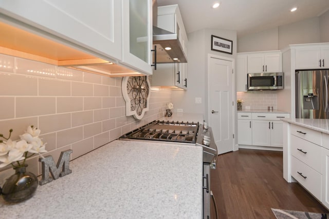 1104 Hershey Rd, Normal, IL 61761 - kitchen featuring appliances with stainless steel finishes, tasteful backsplash, white cabinetry, wall chimney range hood, and dark wood-type flooring