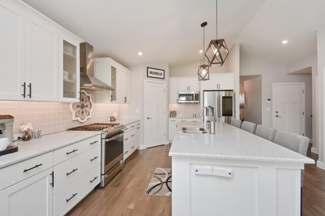 1104 Hershey Rd, Normal, IL 61761 - kitchen featuring wall chimney range hood, stainless steel appliances, a kitchen bar, decorative backsplash, and a kitchen island with sink