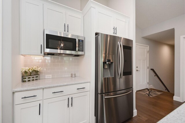 1104 Hershey Rd, Normal, IL 61761 - kitchen featuring stainless steel appliances, tasteful backsplash, white cabinetry, dark wood-style floors, and light stone counters