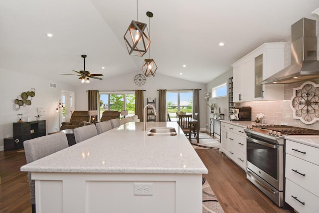 1104 Hershey Rd, Normal, IL 61761 - kitchen with wall chimney exhaust hood, gas stove, a center island with sink, lofted ceiling, and white cabinetry