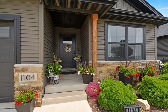 1104 Hershey Rd, Normal, IL 61761 - doorway to property with stone siding, covered porch, and board and batten siding