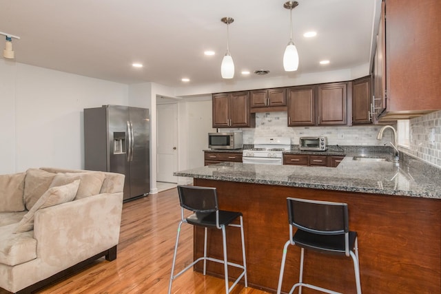 1504 Pfingsten Rd, Glenview, IL 60025 - kitchen featuring appliances with stainless steel finishes, a peninsula, light wood-type flooring, tasteful backsplash, and dark stone counters