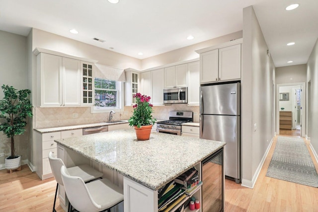 1347 W Washington Blvd Unit 2D, Chicago, IL 60607 - kitchen featuring stainless steel appliances, wine cooler, light wood-style floors, a center island, and light stone countertops