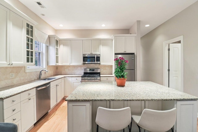 1347 W Washington Blvd Unit 2D, Chicago, IL 60607 - kitchen with stainless steel appliances, a kitchen island, light wood-style floors, a kitchen breakfast bar, and tasteful backsplash