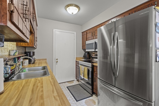 7250 W 84th St Unit C, Bridgeview, IL 60455 - kitchen with appliances with stainless steel finishes, a sink, backsplash, butcher block counters, and brown cabinetry