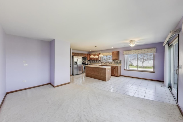 21436 W Larch Ct, Plainfield, IL 60544 - kitchen featuring stainless steel appliances, backsplash, a center island, light countertops, and brown cabinets