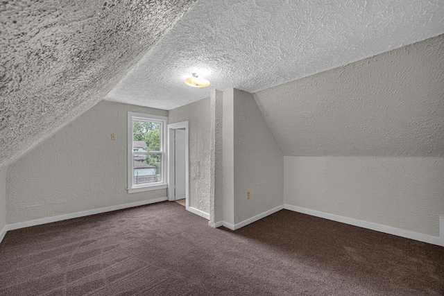 207 Iowa Ave, Joliet, IL 60433 - additional living space featuring a textured ceiling, a textured wall, lofted ceiling, dark colored carpet, and baseboards