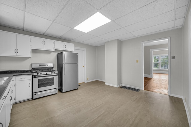 207 Iowa Ave, Joliet, IL 60433 - kitchen featuring appliances with stainless steel finishes, dark countertops, light wood-style flooring, a drop ceiling, and white cabinetry