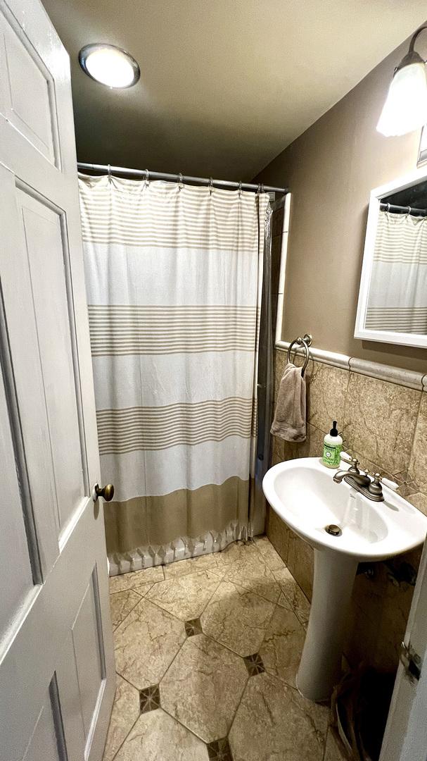 644 Genesee Ave, Morrison, IL 61270 - bathroom featuring a wainscoted wall, tile walls, and a shower with curtain