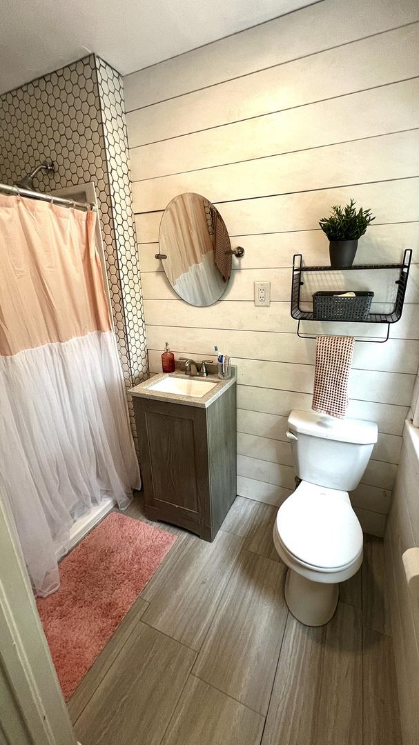 644 Genesee Ave, Morrison, IL 61270 - full bathroom featuring vanity, wood finished floors, curtained shower, and wood walls