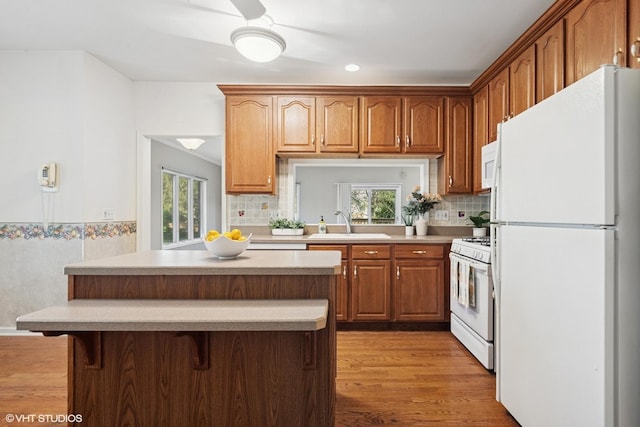 122 Santa Fe Ln, Willow Springs, IL 60480 - kitchen featuring white appliances, wood finished floors, a center island, light countertops, and a breakfast bar